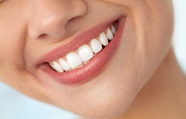 The image shows a close-up of a person smiling with white teeth, focusing on oral health care.