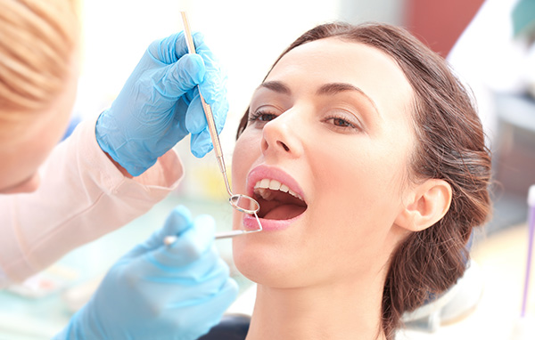 Woman receiving dental treatment with a dentist applying a mouthguard using a dental drill.