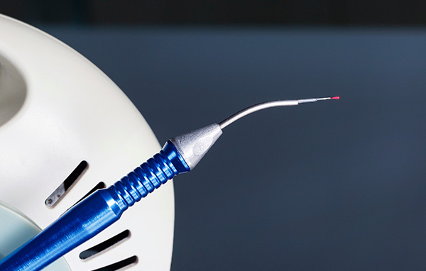 The image displays a close-up view of an electric toothbrush with a blue bristle head and a single red bristle, indicating one bristle is missing.