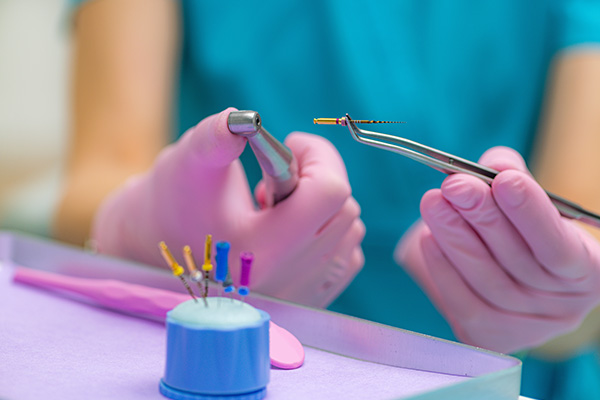 A dental hygienist working at a desk with dental tools, wearing gloves and holding a dental pick.