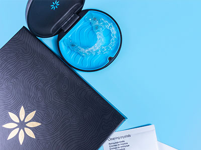 A blue toothbrush with white bristles placed on a black box against a light blue background.