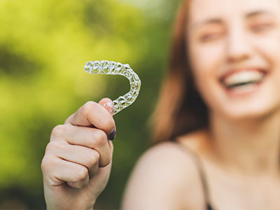 A smiling woman holding up a toothbrush with bristles.