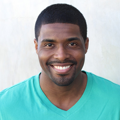An elderly couple poses closely together with smiles, embracing each other in front of a scenic backdrop.