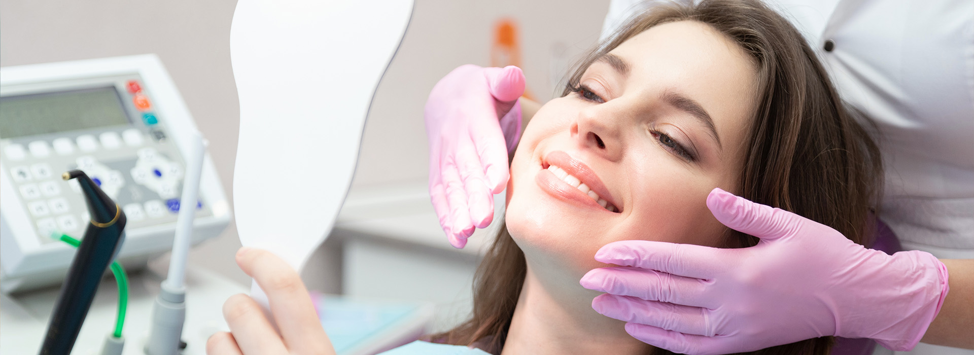 A woman receiving dental care with a dentist using a handheld device on her mouth.