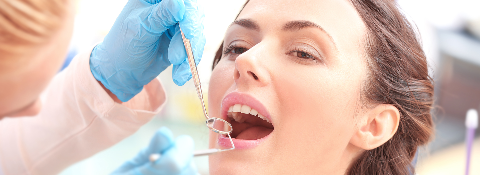 A woman receiving dental care with a syringe being injected into her mouth by a professional wearing gloves.