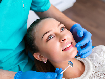 A dental hygienist is performing a cleaning procedure on a patient s teeth using dental instruments.